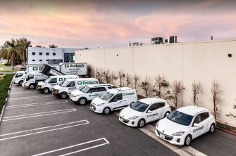 A row of vehicles belonging to Protech Construction parked outside a building, showcasing the company's branding and logo.
