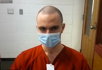 Teenager in red prison attire and a mask appearing in court following a hacking conviction.
