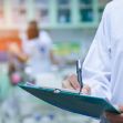 A healthcare professional in a lab coat holding a clipboard while writing notes in a clinical setting. A healthcare professional in a lab coat holding a clipboard while writing notes in a clinical setting.