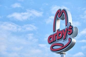 Arby's restaurant sign against a blue sky with clouds.