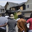 A group of individuals watching the aftermath of a house fire in a suburban neighborhood. A group of individuals watching the aftermath of a house fire in a suburban neighborhood.