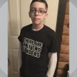 A young boy stands in front of a door wearing a T-shirt that reads, "There are only two genders." A young boy stands in front of a door wearing a T-shirt that reads, "There are only two genders."