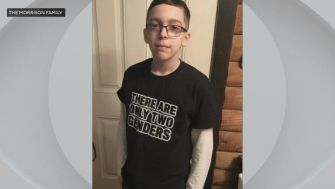 A young boy stands in front of a door wearing a T-shirt that reads, "There are only two genders."