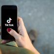 A person holding a smartphone displaying the TikTok logo on the screen. A person holding a smartphone displaying the TikTok logo on the screen.