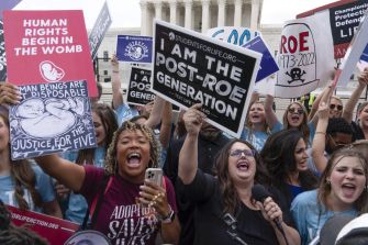 A group of activists holding signs at a rally outside the Supreme Court, expressing anti-abortion sentiment and highlighting their stance on reproductive rights.