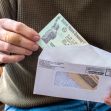 A person holding a check partially pulled from an envelope, with a focus on the check. A person holding a check partially pulled from an envelope, with a focus on the check.