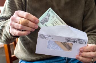 A person holding a check partially pulled from an envelope, with a focus on the check.