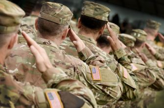 A group of Army veterans in military uniforms saluting.