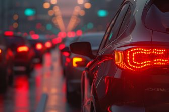 A line of cars with illuminated tail lights in a traffic jam during twilight.