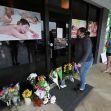 Jessica Lang pauses and places her hand on the door in a moment of grief after dropping off flowers with her daughter Summer at Youngs Asian Massage parlor where four people were killed in Acworth, Ga.