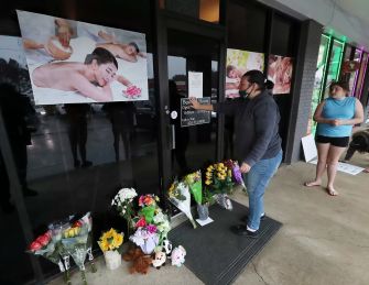 A woman places flowers at the entrance of a massage spa in Atlanta as a memorial for the victims of a recent shooting spree.