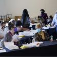 A group of people in an election office environment reviewing absentee ballots, with some individuals engaged in conversation and wearing masks. A group of people in an election office environment reviewing absentee ballots, with some individuals engaged in conversation and wearing masks.