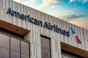 Signage of American Airlines on a building with a cloudy sky in the background.