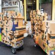 Stacks of Amazon packages on carts beside a delivery van. Stacks of Amazon packages on carts beside a delivery van.
