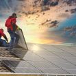 Workers installing solar panels on a roof at sunset. Workers installing solar panels on a roof at sunset.