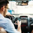 A person texting on a smartphone while driving a car. A person texting on a smartphone while driving a car.