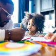 A child coloring with a parent at a table, surrounded by crayons and drawings. A child coloring with a parent at a table, surrounded by crayons and drawings.